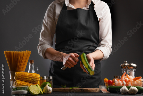Chef cooks Shrimp Stir Fry, peel zucchini. Seafood. Against the background of ingredients. Asian cuisine, Oriental food. Culinary background, recipe book, home cooking and recipes.