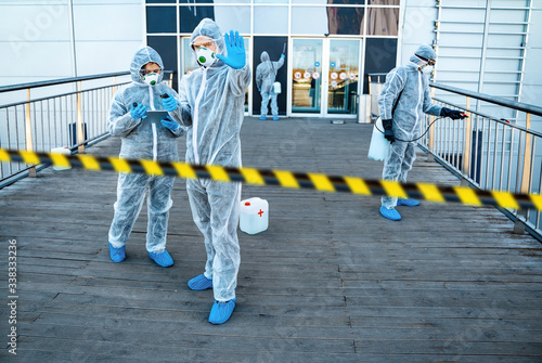 Healthcare worker showing stop gesture. Team of healthcare workers wearing hazmat suits working together to control an outbreak in the city photo