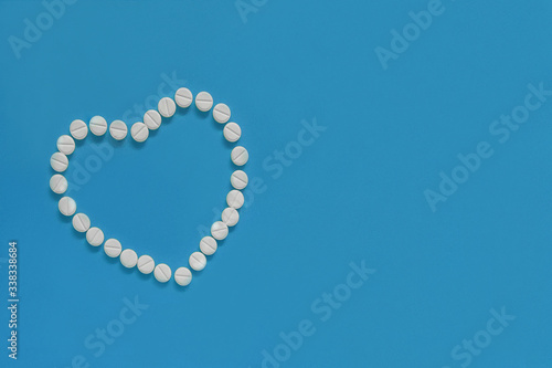 The heart made of tablets and pills on blue background