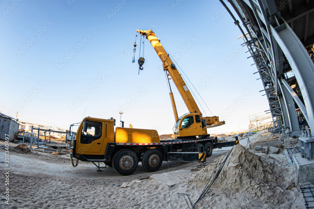 A large yellow truck crane stands ready to work on the construction site
