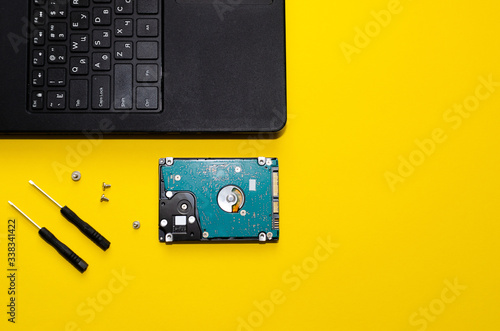 hard drive, laptop and screwdrivers on a yellow background
