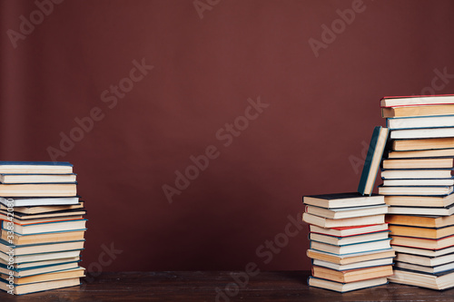 many stacks of educational books to study in the university library on a brown background