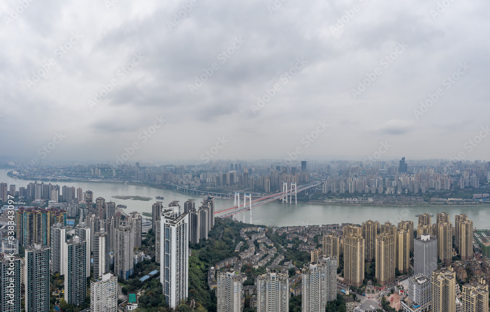Fototapeta premium Aerial drone shot of Caiyuanba Bridge over Yangtze river and dense riverside residential building along in Chongqing, China
