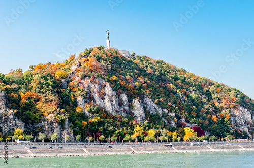 Gellért Hill in Budapest in autumn colors with the Liberty Statue on the top.