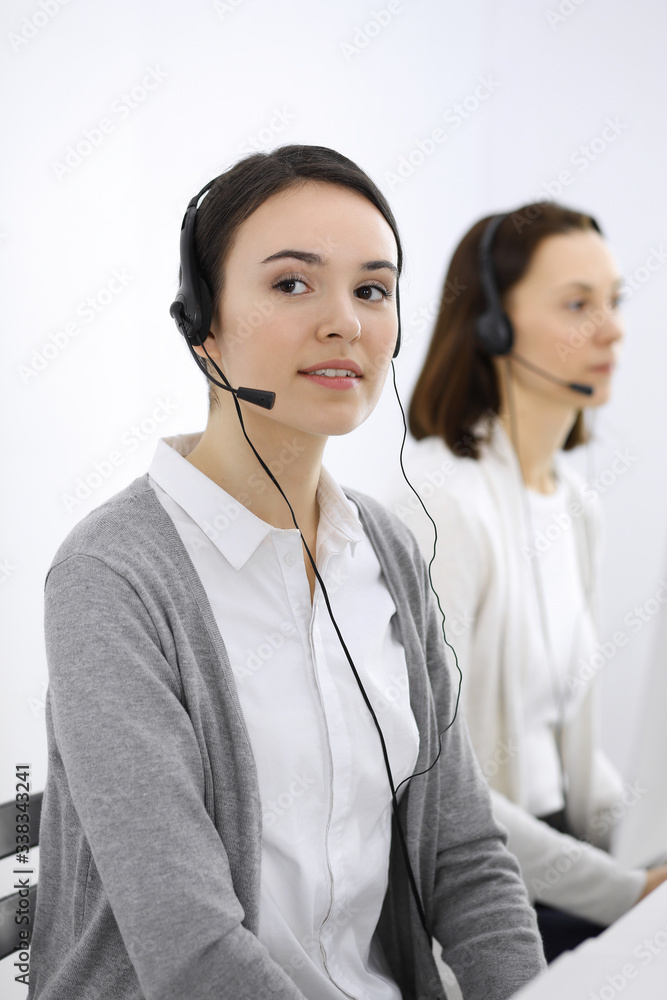 Call center. Casual dressed woman working in headset with diverse colleagues at office. Business concept Call center. Casual dressed woman working in headset with diverse colleagues at office. Business concept