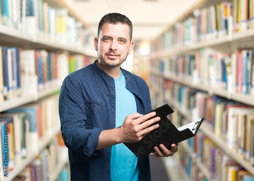 Young man wearing a blue outfit. Holding a black folder. Looking confident.