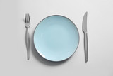 Clean plate and cutlery on light background