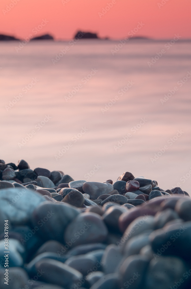 Obraz premium Pretty red sunset over a pebble beach in Menorca, Spain