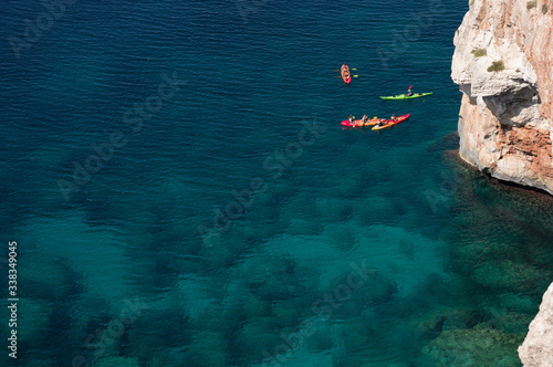 Group of bright coloured kayakers in the mediterranean sea by the cliffs © Nathan
