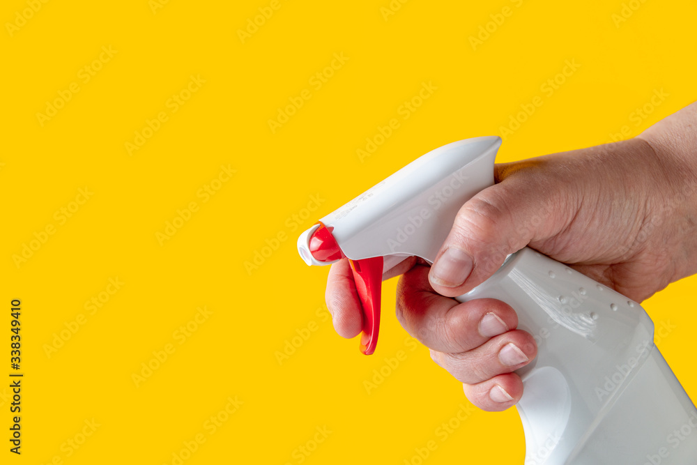 Fototapeta premium Woman holding spray cleaner in her hands on a yellow background