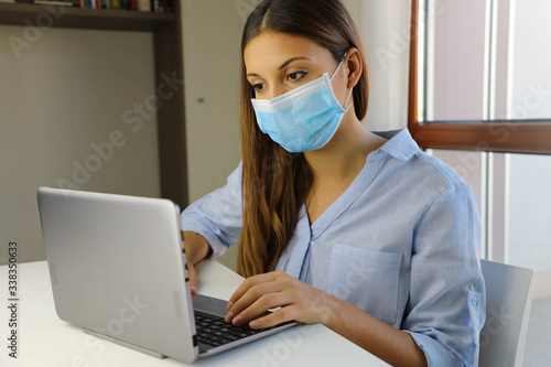 COVID-19 Pandemic Coronavirus Home Schooling E-learning Student Girl Mask Study from Home Laptop. Quarantine young woman studying from home for virus disease SARS-CoV-2. Smart school concept.
