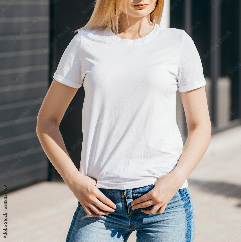 Girl wearing white t-shirt posing against street , urban clothing style. Street photography - obrazy, fototapety, plakaty 