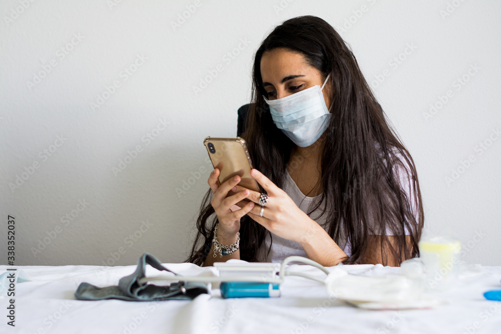 COVID-19 Pandemic Coronavirus Mask Woman nurse hospital or home isolation auto quarantine for virus SARS-CoV-2. Girl voluntary isolation surgical mask with a mobile phone. Disease 2019.