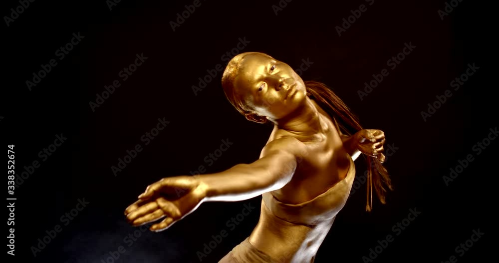 woman looks like golden statue of oriental goddess is dancing, studio shot woman looks like golden statue of oriental goddess is dancing, studio shot