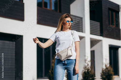 Young model girl in white t-shirt and glasses with waist bag