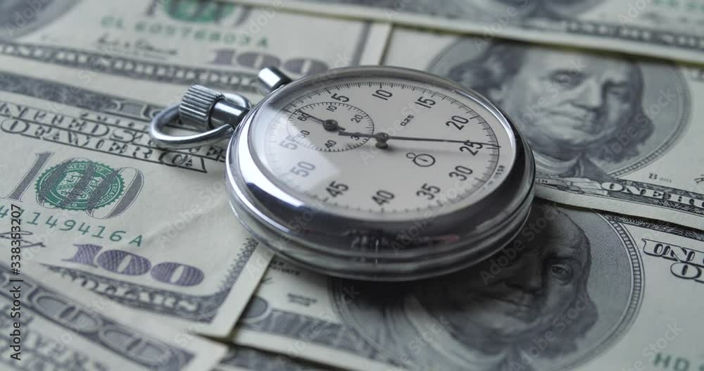 The stopwatch lies on the dollars. Time is money concept. The stopwatch lies on the dollars. Time is money concept.