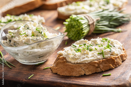 Fotografi A bowl of homemade cream cheese spread with chopped chives surrounded by bread s