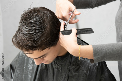 Mother cutting her son's hair in his home bathroom