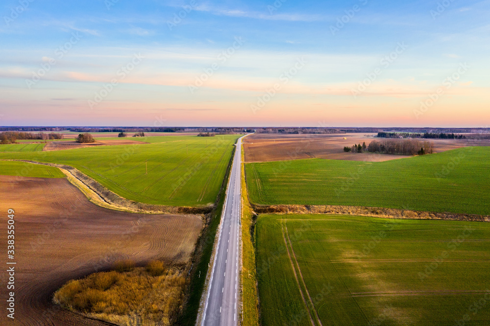 Aerial view of a highway passing through spring agricultural fields at sunset