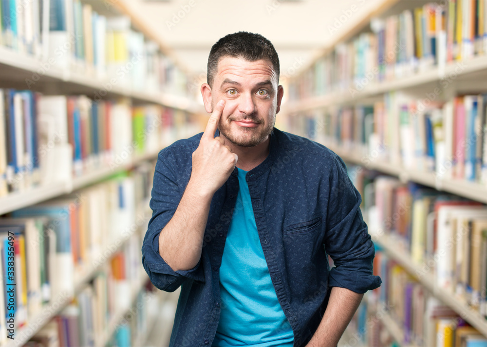 Young man wearing a blue outfit. Pointing to his eye. Young man wearing a blue outfit. Pointing to his eye.