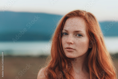 Incredible young woman with long curly hair and freckles face. photo
