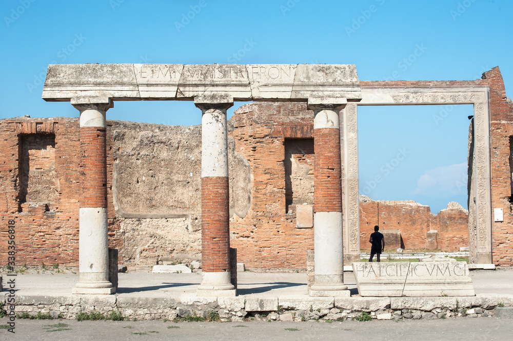 A tourist stands in the doorway of the Building of Eumachia, Pompeii, Italy