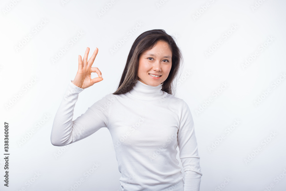 Photo of smiling female student is showing ok gesture on white background. Photo of smiling female student is showing ok gesture on white background.