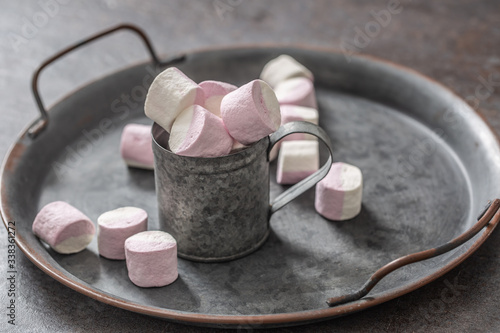 Metallic vintage tray, surface and cup with pink and white marshmallows inside the cup and scattered around the tray