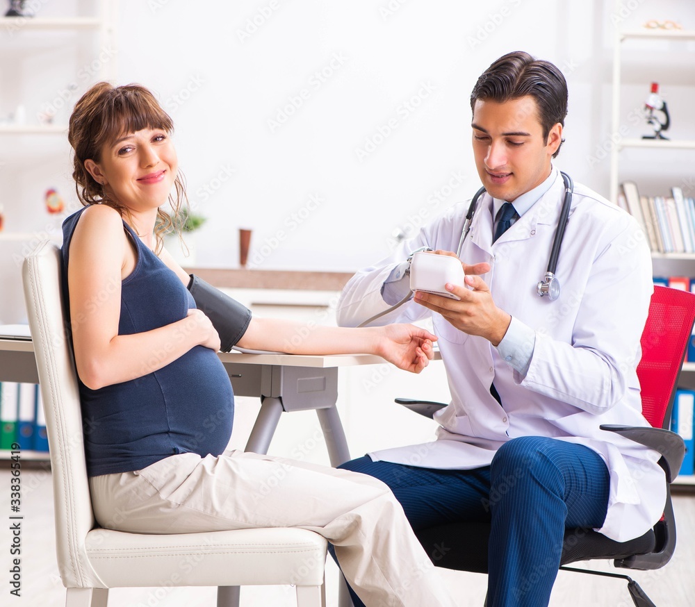 Fototapeta premium Young doctor checking pregnant woman's blood pressure