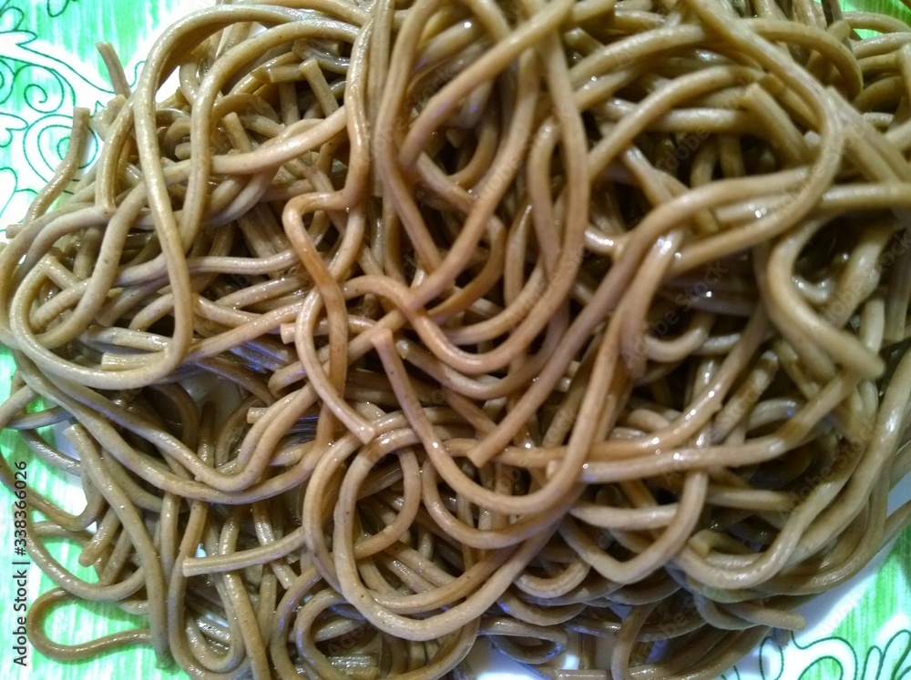 Budget cooked dish of brown buckwheat spaghetti. Cheap food. The economic and financial crisis concept. There are no products in the supermarket. Cut out the expense. Noodles. Selective focus Budget cooked dish of brown buckwheat spaghetti. Cheap food. The economic and financial crisis concept. There are no products in the supermarket. Cut out the expense. Noodles. Selective focus