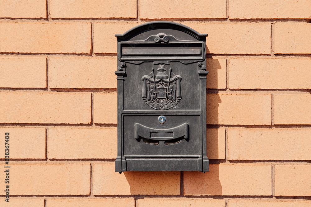 black metal mailbox with patterns on a brick wall black metal mailbox with patterns on a brick wall