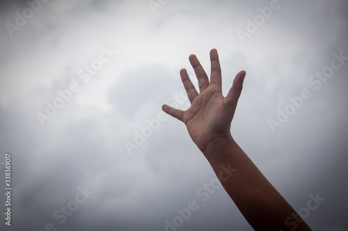 Hand raised high with sky in background