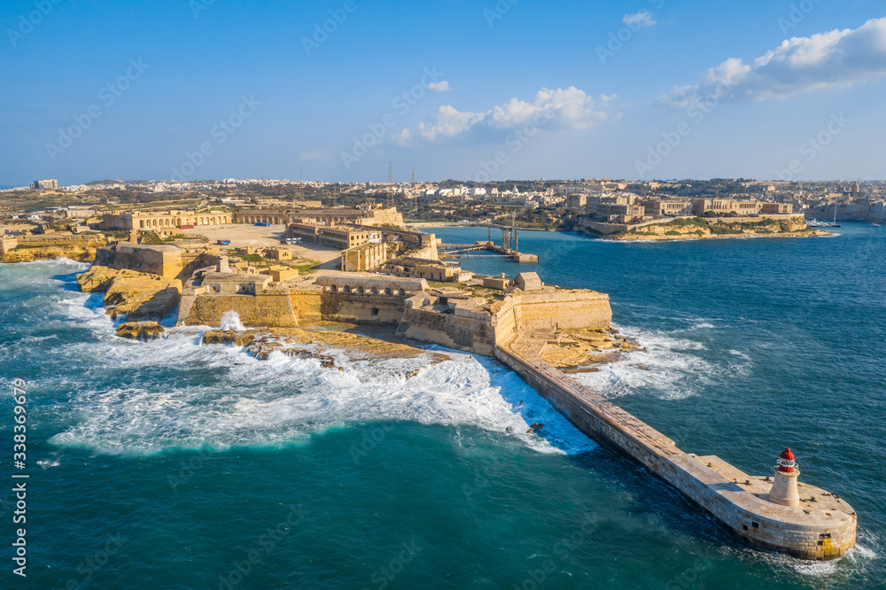 Aerial  view of red lighthouse and Fort Ricasoli. Big stormy waves, Mediterranean sea. Malta 