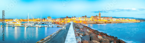 Panoramic evening cityscape of Alghero port and historical part of cit