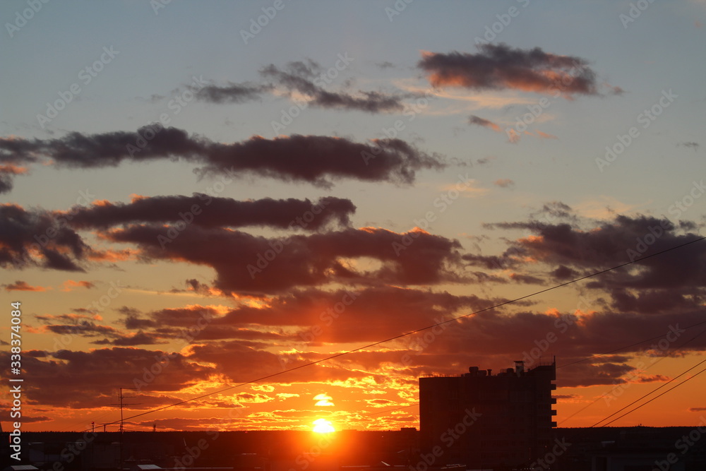 Fototapeta premium Clouds in the blue sky at sunset or dawn backlit by the sun. Place for text and design.