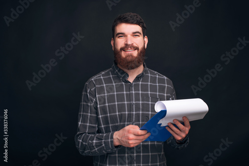 Portrait of handsome young man holding clip board and looking confident at the camera