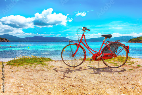 Astonishing morning view on beach Tramariglia and red vintage bicycle parked on sand.