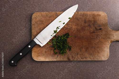 food ingredients, parsley herb roughly chopped on chopping board next to big knife photo