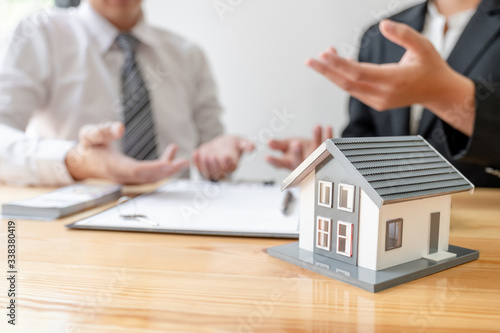 A real estate agent with House model is talking to clients about buying home insurance. Home insurance concept