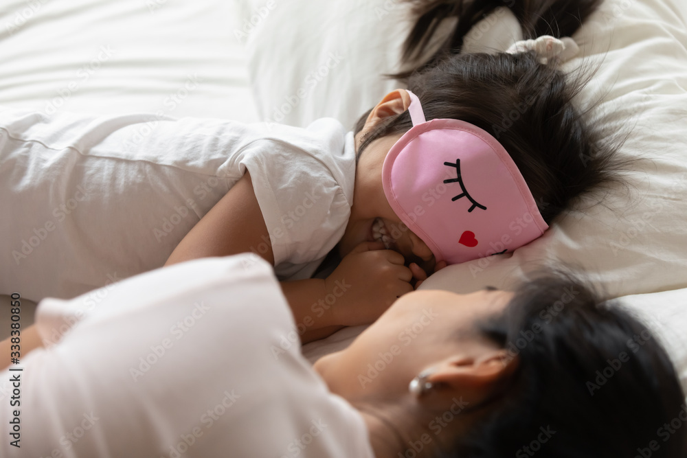 Φωτογραφία Close up of toddler girl wears sleeping eye mask girlish pink color smiles enjoy rest time lying in bed with mother