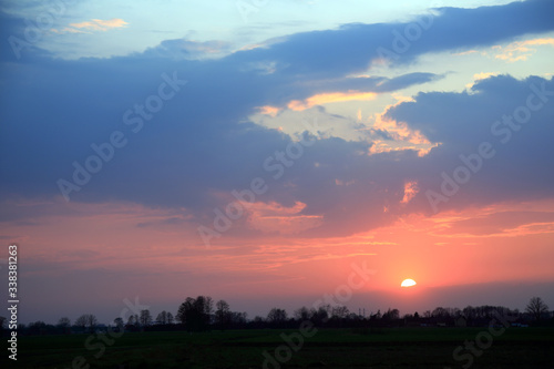 Kolorowy zachód słońca nad obszarem wiejskim, złote chmury.
