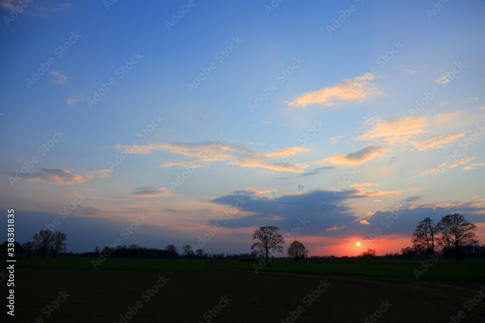 Kolorowy zachód słońca nad obszarem wiejskim, złote chmury.