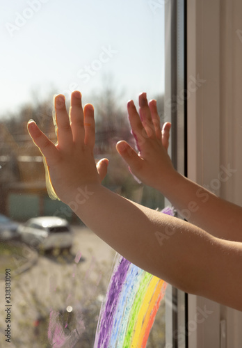 children's hands on the window glass make colored palm prints in yellow and purple, self-isolation