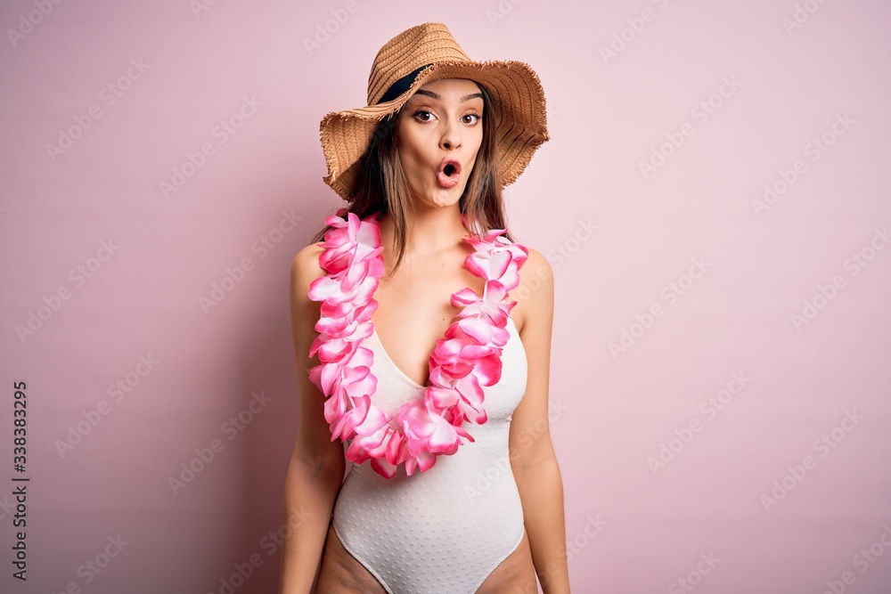 Young beautiful brunette woman on vacation wearing swimsuit and Hawaiian flowers lei afraid and shocked with surprise expression, fear and excited face. Young beautiful brunette woman on vacation wearing swimsuit and Hawaiian flowers lei afraid and shocked with surprise expression, fear and excited face.