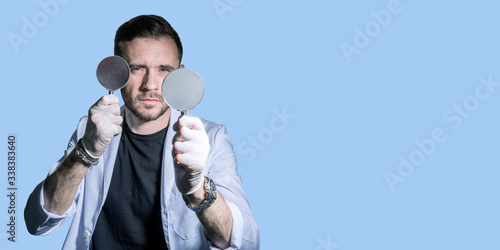 man in a white coat holds a magnifying glass in crayfish in the hope of finding a cure for the epidemic of the virus. figure of a doctor on a blue background banner. Free place. Concept - vaccine photo