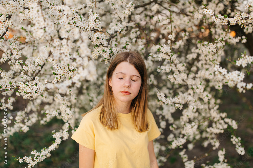 Portrait of young beautiful blonde woman near blooming tree with white flowers on a sunny day. Spring, girl near a flowering tree.beautiful girl in a yellow t-shirt near a flowering tree Portrait of young beautiful blonde woman near blooming tree with white flowers on a sunny day. Spring, girl near a flowering tree.beautiful girl in a yellow t-shirt near a flowering tree
