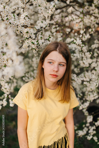 Portrait of young beautiful blonde woman near blooming tree with white flowers on a sunny day. Spring, girl near a flowering tree.beautiful girl in a yellow t-shirt near a flowering tree