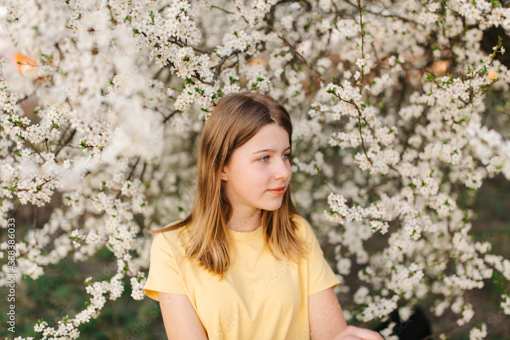 portrait of sad young woman in protective medical face mask with flowers near blooming tree in spring time. Coronavirus protection. epidemic of coronavirus. the aroma a tree in the garden on a spring portrait of sad young woman in protective medical face mask with flowers near blooming tree in spring time. Coronavirus protection. epidemic of coronavirus. the aroma a tree in the garden on a spring