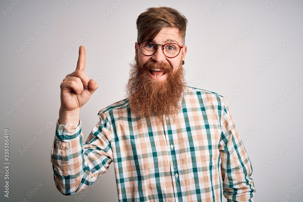 Handsome Irish redhead man with beard wearing glasses and hipster shirt pointing finger up with successful idea. Exited and happy. Number one. Handsome Irish redhead man with beard wearing glasses and hipster shirt pointing finger up with successful idea. Exited and happy. Number one.