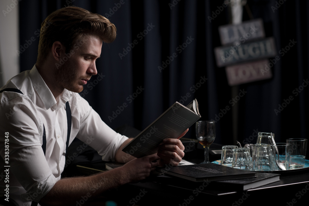 Fototapeta premium Junger Mann beim lesen mit einem Glas 